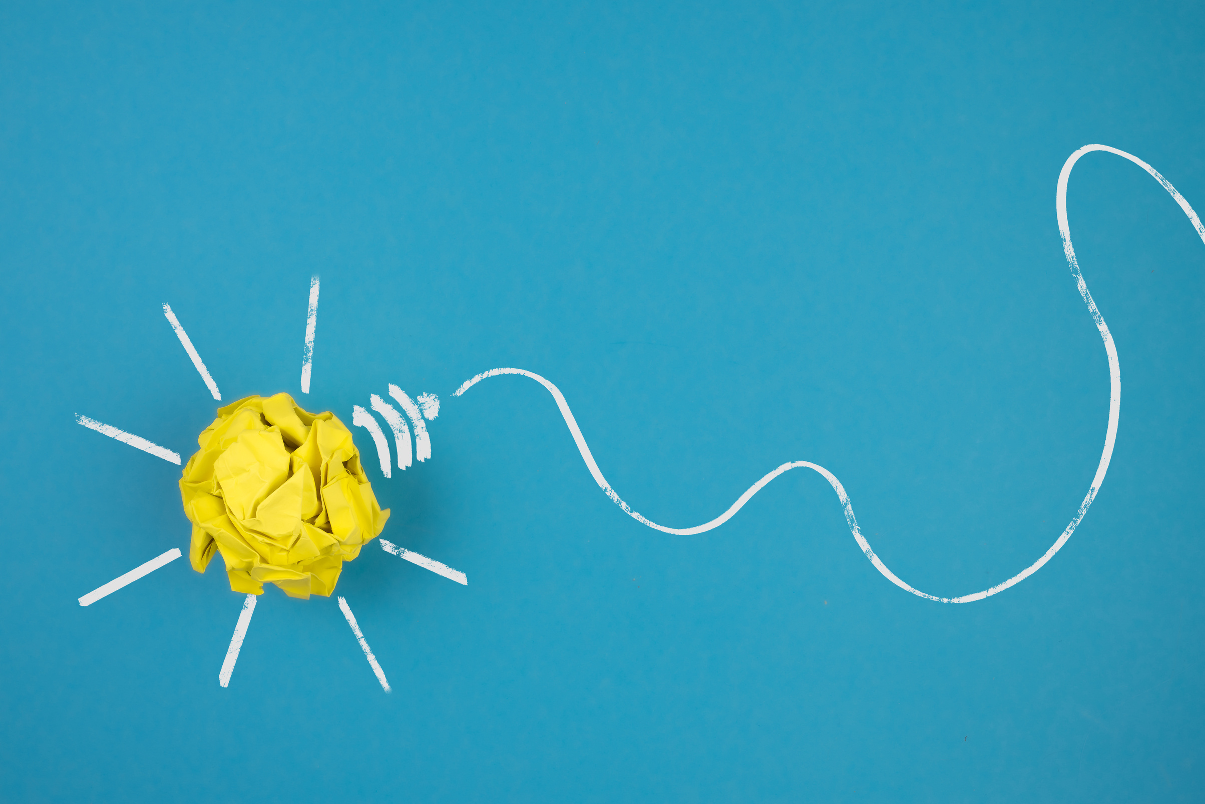 light bulb made of crumpled-up yellow paper on blue background
